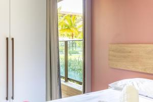 a bedroom with a window looking out at a garden at Praia Muro Alto paradisíaco, Flat de 2 quartos. in Porto De Galinhas +34 photos