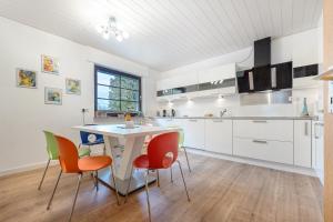 eine Küche mit weißen Schränken sowie einem Tisch und Stühlen in der Unterkunft Gästehaus am Mühlenteich in Schieder-Schwalenberg
