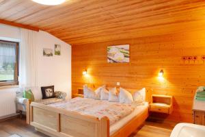 1 dormitorio con 1 cama y pared de madera en Haus Bergfrieden en Au im Bregenzerwald