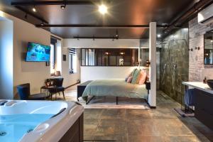 1 dormitorio con cama y bañera en La Forge By CV - Jacuzzi, Sauna, plat repas et petit déjeuner en Eppe-Sauvage