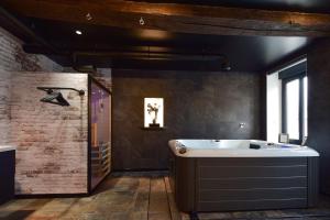 y baño con bañera y lavamanos. en La Forge By CV - Jacuzzi, Sauna, plat repas et petit déjeuner en Eppe-Sauvage