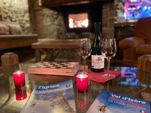 einen Tisch mit zwei Gläsern, zwei Weinflaschen und Kerzen in der Unterkunft Chalet 1728 - La Reculaz - 2 minutes from Val D'isere in Tignes
