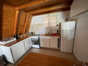 cocina con electrodomésticos blancos y techo de madera en Cabañas abuelo pepe en Necochea