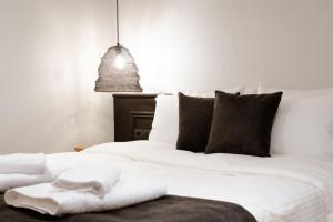 ein Bett mit weißer Bettwäsche und schwarzen Kissen in der Unterkunft Nostos - Luxury Apartment in Agrinio in Agrinio