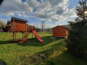 une aire de jeux avec toboggan et une maison dans l'établissement Drevenica Deni, à Osturňa