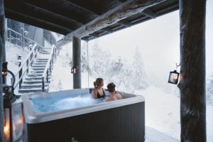 Due persone sedute in una vasca idromassaggio nella neve di Ruka Peak - Boutique Hotel & Restaurant a Ruka