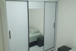 Cette chambre dispose d'un placard avec miroir et d'un lit. dans l'établissement Apartamento no Condomínio Roma com estacionamento, à Pôrto Santana
