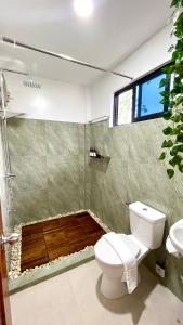 a bathroom with a toilet and a shower with a window at Namal Apartelle - Free Scooter & GYM access in El Nido