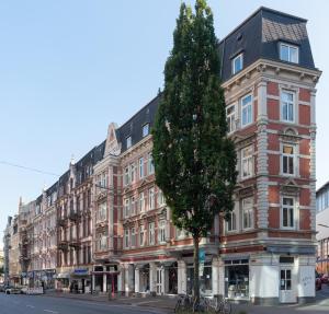 a large brick building with a tree in front of it at Park Lane Business-Apartment in Hamburg