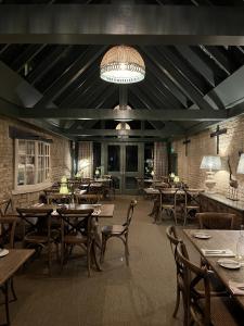 a restaurant with wooden tables and chairs and a chandelier at White Hart Ufford in Ufford