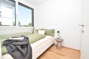 a white bedroom with a bed and a window at Ferienwohnung in Hard am Bodensee in Hard