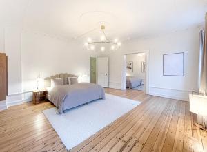 a white bedroom with a bed and a chandelier at Large & Modern 4 Bedroom Flat in Copenhagen