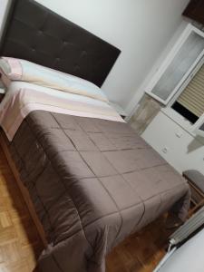 un grande letto con testiera nera in una stanza di Apartamento Abrantes a Madrid