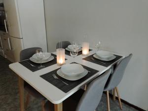 Huoneisto Ketunpesä في Taivalkoski: طاولة بيضاء مع كراسي وصحون وكؤوس للنبيذ