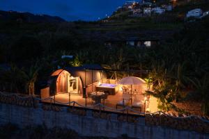 uma tenda com mesa, cadeiras e guarda-sóis à noite em Glamping Maracujá - Oasis Paradise em Ribeira Brava