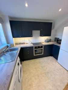 a kitchen with blue cabinets and a white refrigerator at Newly refurbished 2 bed- Didcot 