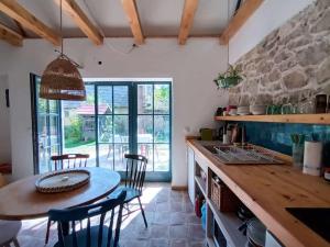 a kitchen with a table and chairs and a stone wall at ZebRegény Vendégház in Zebegény