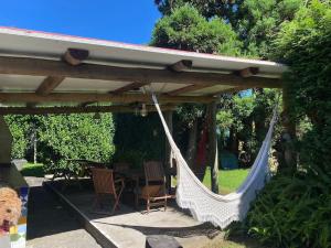 a hammock under a pergola with a table and chairs at Caboz Inn in Horta