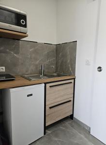 a kitchen with a sink and a microwave at Un petit coin de paradis à La Réunion in Saint-Joseph