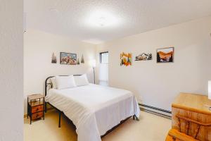 1 dormitorio con 1 cama con sábanas blancas y cuadros en la pared en Shimmering Summit Hideaway, en Mount Crested Butte