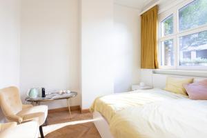 a bedroom with a bed and a table and a window at Pauline Loveling apartment with quiet garden and 2 bathrooms in Antwerp