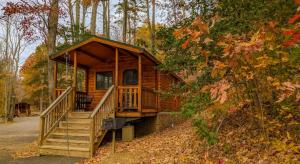 a log cabin with a porch and stairs in the woods at Wilderness Presidential Resort in Spotsylvania
