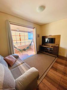 uma sala de estar com um sofá e uma televisão em Flat com vista para o Mar e Garagem em Torres
