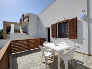 una mesa blanca y sillas en el balcón de una casa en TRISCINA SELINUNTE BEACH, en Triscina