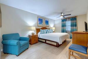 The Resort on Cocoa Beach, a VRI resort في كوكاو بيتش: غرفة نوم بسرير وكرسي ازرق