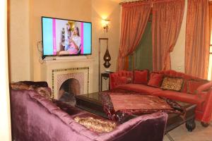 Il comprend un salon doté d'un canapé et d'une télévision à écran plat. dans l'établissement nakhil villa palm, à Marrakech