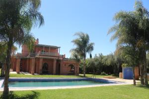 une maison avec une piscine et des palmiers dans l'établissement nakhil villa palm, à Marrakech