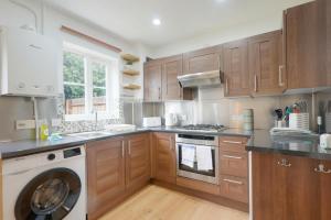 a kitchen with wooden cabinets and a washing machine at Wonderful 2 bed accommodates 6 in Shenley Brook End