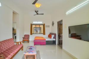 a living room with a couch and a bed and a tv at Amazing Pool View Candolim Goa 1BHK Apartment in Candolim