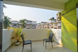 two chairs on a balcony with buildings in the background at Amazing Pool View Candolim Goa 1BHK Apartment in Candolim