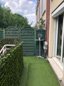 un jardin avec une clôture verte et une table dans l'établissement Two bedrooms apartment- ideal location near Paris, à Suresnes