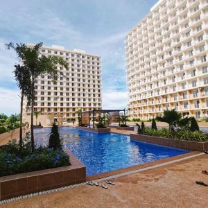 un grande edificio con una piscina di fronte a un edificio di Affordable Condo w/ Wi-Fi, Pool & Shower Heater a Lapu Lapu City