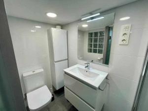 a white bathroom with a toilet and a sink at Utsa Eski -Piso con encanto en 1ª linea de puerto in Bermeo +28 photos