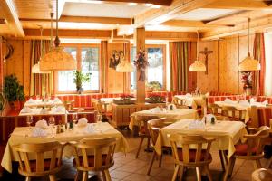 un ristorante con tavoli e sedie bianchi e finestre di Hotel Pension Haid a Sankt Leonhard im Pitztal