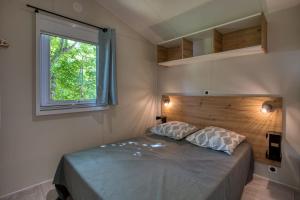 a bedroom with a large bed with a window at Camping du Lac de Grolejac in Groléjac