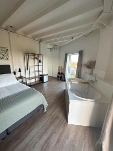 1 dormitorio con cama, bañera y ventana en Hotel de Watertoren, en Dordrecht