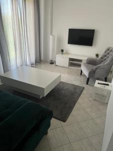 ein Wohnzimmer mit einem weißen Tisch und einem TV in der Unterkunft MAGIC M Apartment in Mali Mokri Lug