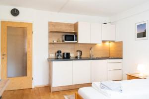 cocina con armarios blancos y lavabo en una habitación en Innsbruck Studio by MO, en Innsbruck
