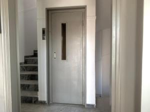 a white door in a white room with stairs at Perfect location for the Olympic stadium Would sleep 4 comfortably for an overnight stay in Athens