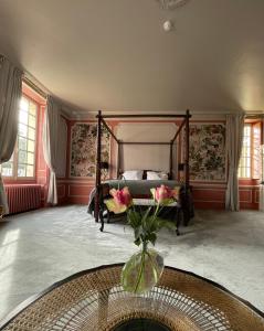 a bedroom with a bed and a vase with flowers at Château de la Huberdière in Nazelles