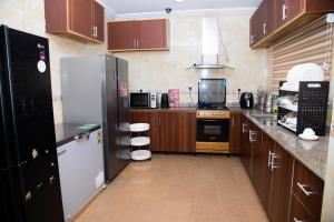 kuchnia z drewnianymi szafkami i czarną lodówką w obiekcie VelvetRose Cottage w mieście Araromi