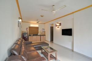 - un salon avec un canapé en cuir et une table dans l'établissement Amazing Pool View Candolim Goa 2BHK Apartment, à Candolim