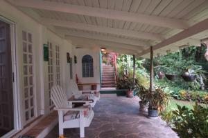 a porch with white chairs and stairs and plants at Apartamento Karibu in Manuel Antonio