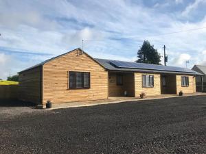 una casa de madera con paneles solares. en Kenns Farm - 2 Beautiful Barns en Carterton