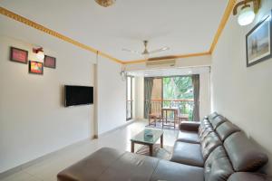 - un salon avec un canapé et une télévision dans l'établissement Amazing Pool View Candolim Goa 2BHK Apartment, à Candolim