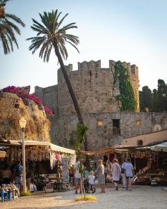 a group of people walking around a market in front of a castle at Emelia Cozy Apartment in Rhodes Town